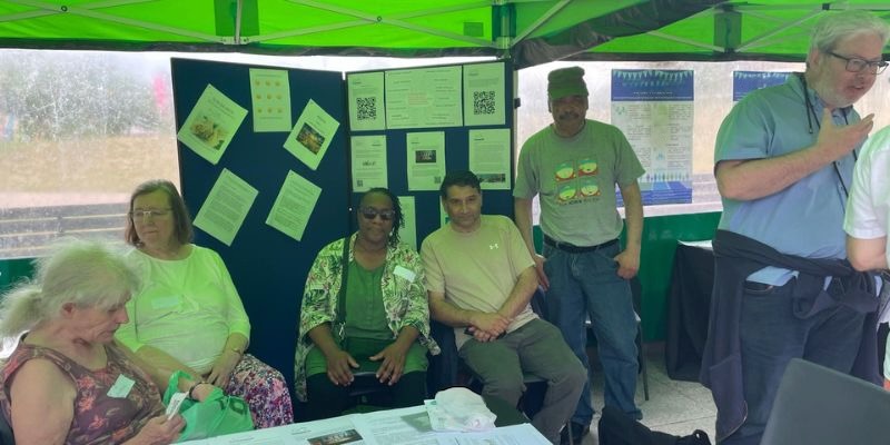 photo showing six Suresearch members at event stall, some seated and some engaging with visitors